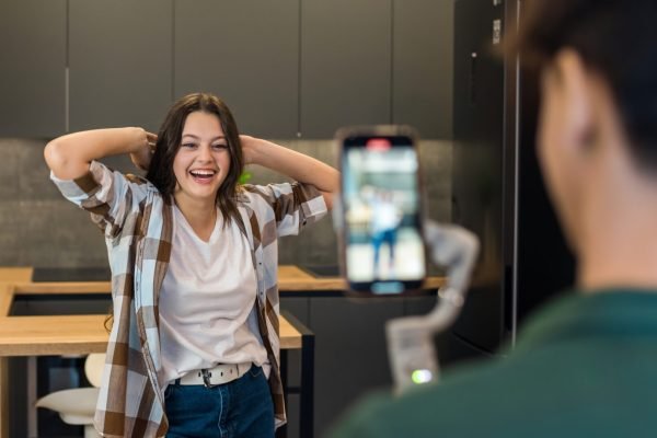 A person recording a young dancing woman blogger influencer on smartphone on a stabiliser in a studio